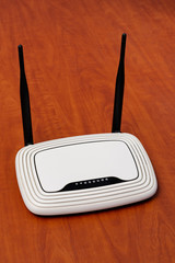 white wi-fi router with black antennas on a wooden table background