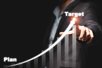 Businessman hand point drawing increase trend arrow and growing chart from plan to target on black background. It is symbol of business investment growth concept.