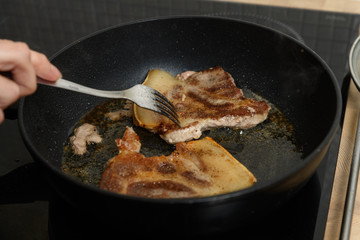 pork chop is cooked in a frying pan in sunflower oil