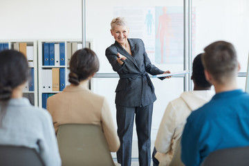 Portrait of mature businesswoman giving speech to audience during seminar, copy space