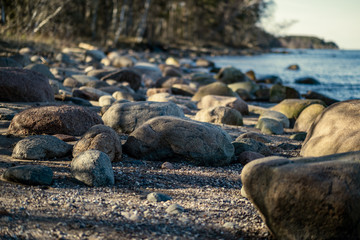 sunny beach with blue water and large rocks in the sand