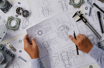 Engineer technician designing drawings mechanical parts engineering Engine.manufacturing factory Industry Industrial work project blueprints measuring bearings caliper tools