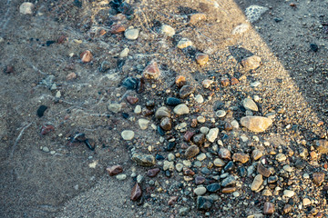 sunny beach with blue water and large rocks in the sand