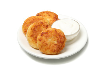 Plate with cheese pancakes and sour cream isolated on white background