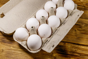 Raw chicken eggs in cardboard egg box on wooden table
