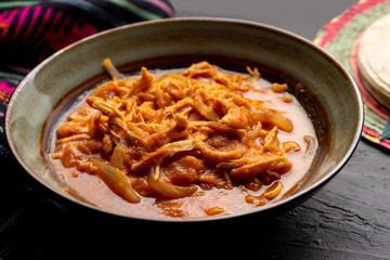 Mexican chicken tinga with chipotle sauce on dark background