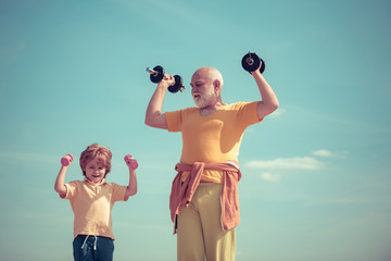 Portrait of senior man and cute child lifting dumbbells. I love sport. Be in motion. Motivation and sport example concept. Body care and healthcare.