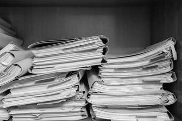 Paper documents stacked in archive. Documents on the shelves of archive room. Office shelves in the closet full of files. black and white photo