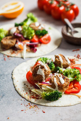 Falafel with pita, vegetables and tahini dressing.