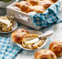 Delicious breakfast traditional easter hot cross bun with the addition of fresh butter on a wooden...