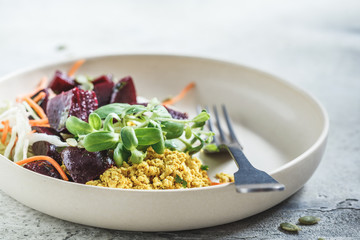 Vegan lunch salad with baked beets, tofu scramble and vegetables in a white plate.