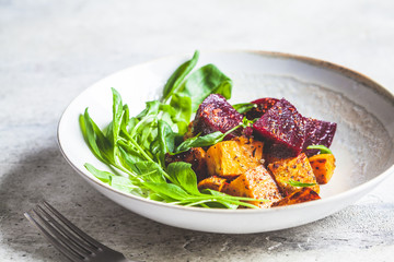 Baked beetroot and sweet potato with spinach salad. Vegan food concept.