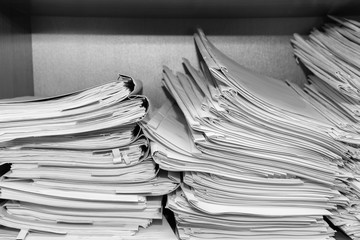Paper documents stacked in archive. Documents on the shelves of archive room. Office shelves in the closet full of files. black and white photo