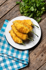 Mexican jalapeno poppers stuffed with cheese and breaded on wooden background