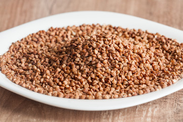 Buckwheat groats on a white plate with blurred background and foreground