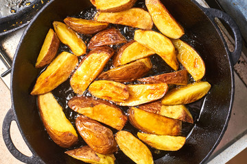 Fried crispy potatoes in oil in a pan. Cooking potatoes in a rustic way.