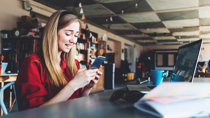Upset woman looking at the phone screen, while sitting in the spacious loft workspace