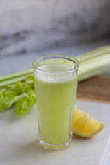 Celery juice in a  glass.  view over a rustic marble white  background.