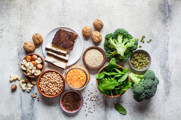Vegan sources of protein, background, top view. Tofu, chickpeas, lentils, nuts, spinach and broccoli - vegetable proteins.
