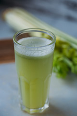 Celery juice in a  glass.  view over a rustic marble white  background.