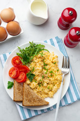 scrambled eggs, tomatoes, toasted bread and greens  for breakfast