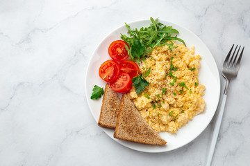 scrambled eggs, tomatoes, toasted bread and greens  for breakfast