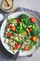 Vegan quinoa salad with tofu, broccoli, tomatoes and nutty dressing. Healthy food concept.