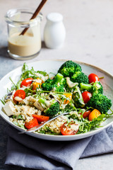 Vegan quinoa salad with tofu, broccoli, tomatoes and nutty dressing. Healthy food concept.
