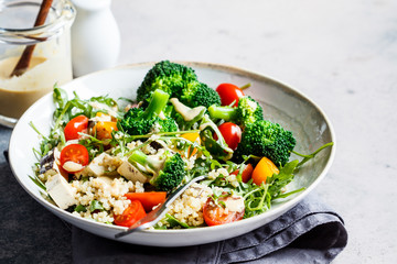 Vegan quinoa salad with tofu, broccoli, tomatoes and nutty dressing. Healthy food concept.