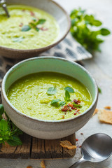 Green peas soup with basil in vintage bowls, vertical shot.