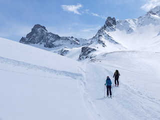 Fototapeta na wymiar Skieurs de ski de randonnée et alpiniste en montagne qui skient sur la neige et la glace en plein soleil des alpes dans le Queyras de saint Véran
