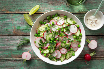 Fresh radish, cucumber and green peas salad in white bowl