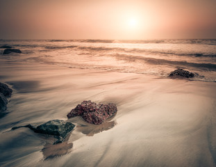 Sunset at tropical beach. Rocks at the ocean coast under evening sun. South India  landscape