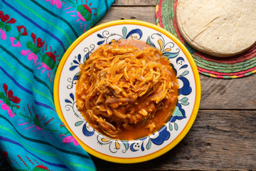 Mexican chicken tinga with chipotle sauce on wooden background