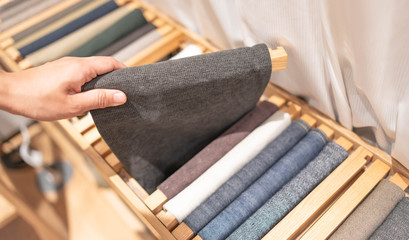 Fototapeta na wymiar Female hand choosing sheet of fabric or textile. Group of Multi-colored Earth Tone fabric