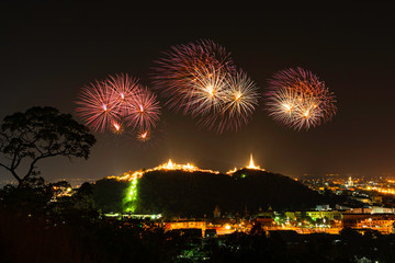 Abstract the colourful fireworks display is shot above the mountains and the golden pagoda of the temple at the annual fireworks festival in Phetchaburi, Thailand.