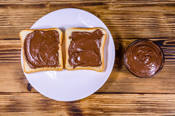 Two sandwiches with chocolate spread on a white plate. Top view