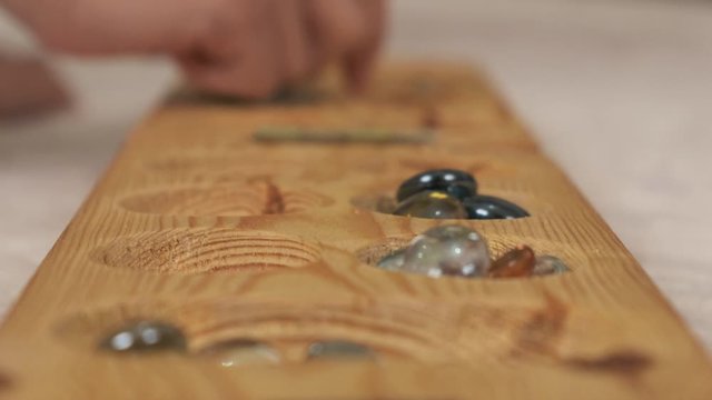 old intelligence games, wooden mancala game, a person playing mancala,