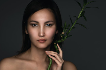 Beautiful asian woman with a bamboo plant in her hands