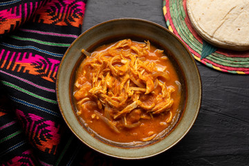 Mexican chicken tinga with chipotle sauce on dark background