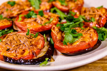 Baked eggplants with tomatoes and cheese in a ceramic plate