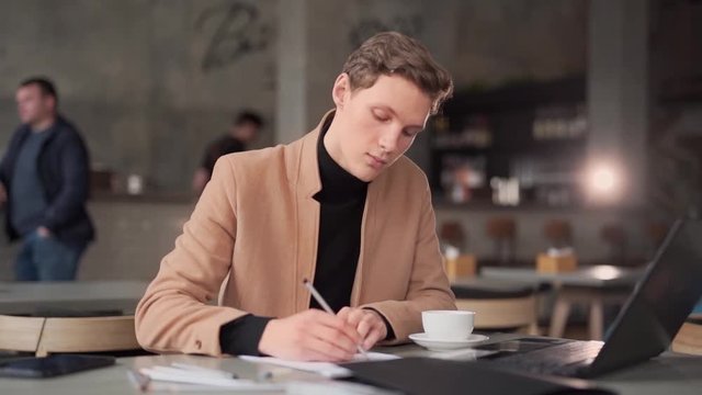 handsome guy draws a sketch in a cafe with a laptop
