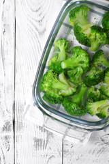 Blanched broccoli cabbage cooling down in cold water in a glass dish on white table