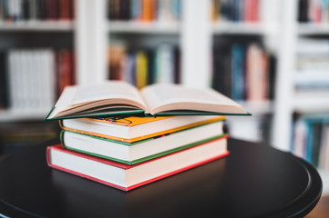 A stack of books on a black table. Library in the background. Stack of books close up.