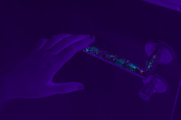 Bacteria, germs and Coronavirus revealed with ultraviolet UV light on dirty door handle surface