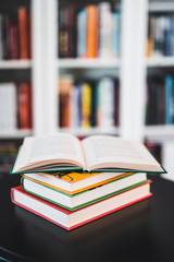 A stack of books on a black table. Library in the background. Stack of books close up.