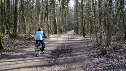 Leśna ścieżka. Rowerzysta samotnie jedzie przez las, wycieczka rowerowa, uprawia sport, trening rowerowy. Kamizelka odblaskowa dla bezpieczeństwa. Rower górski do jeżdżenia po lesie. 