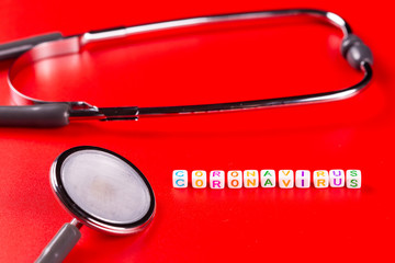 Pandemic and virus concept - Coronavirus text and phonendoscope on red background. Novel...
