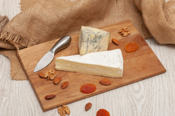brie cheese and roquefort on a board with honey, grapes, dried apricots and nuts