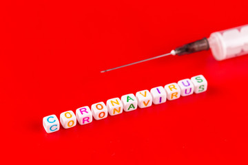 Pandemic and virus concept - Coronavirus text and syringe on red background. Novel coronavirus Covid-19.